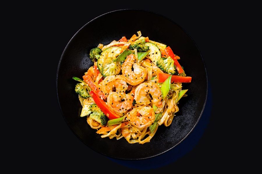 Awokado krevečių wok makaronai juodame dubenyje